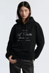 Sudadera marrón con capucha ajustable con cordones y bordado blanco con el texto 'ZAFA A Coruña Established 1975 Rúa Juan Flórez 64-66'.