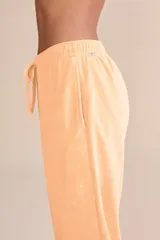 Pantalón jogger color durazno de tejido frosty con superficie plush de tacto suave y aterciopelado. Tiene cintura media con ajuste mediante amarre y bolsillos laterales.