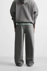 Pantalón jogger negro de corte ancho, confeccionado en tejido de algodón con interior de rizo. Cuenta con cintura elástica ajustable con cordón interior, bolsillos laterales y bolsillo trasero de parche.