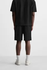 Bermuda negra de corte relaxed fit, con cintura elástica ajustable con cordón, bolsillos frontales y bolsillo trasero de parche.