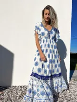 Vestido largo blanco con estampado floral azul, escote en V con bordado y mangas cortas con volados.