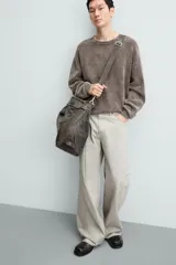 Pantalón de algodón color beige claro, estilo relaxed fit, con cintura ajustable mediante cinturón de tela a juego. Presenta cinco bolsillos, bolsillos laterales de vivo y costuras laterales giradas hacia adelante.