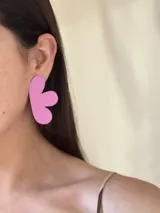 Aros grandes con forma de corazón color fucsia.