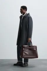Parka larga color verde oscuro, con capucha desmontable, cuello solapa, bolsillos laterales y cierre frontal con cremallera oculta y botones a presión. Incluye chaleco interior acolchado desmontable.