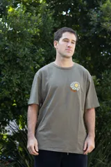 Remera color verde militar de manga corta con cuello redondo y estampado en el pecho con un paisaje de montaña y sol.