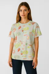 Remera de manga corta color celeste con estampado de plantas, flores y objetos decorativos en tonos naranja, verde y rosa.