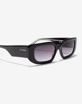 Lentes de sol Hawkers unisex de acetato negro con lentes rectangulares degradadas de gris oscuro a transparente.