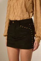 Minifalda negra de poliéster con corte al cuerpo, tiro alto y detalle de tachas doradas decorativas a lo largo de la costura lateral y el bolsillo delantero.