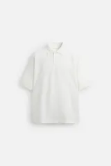 Polo blanco de piqué con corte relaxed fit, cuello solapa y cierre frontal con botones.