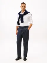 Camisa blanca de corte slim, confeccionada en tejido dobby de algodón elástico con textura sutil. Presenta cuello con botones, puños redondeados con botón y el logo de Tommy Hilfiger bordado en el pecho.