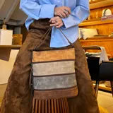 Bandolera marrón con paneles combinados en tonos beige y verde. Tiene apertura superior con cierre, bolsillo frontal con cierre, tres bolsillos internos (dos con cierre), bolsillo trasero con cierre y correa larga regulable.