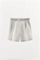 Shorts de algodón color gris claro con estampado de cuadros negros, tiro medio y cintura elástica.