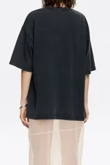 Remera negra de algodón con cuello redondo y manga corta. Estampado frontal con diseño floral abstracto en tonos rosa y marrón.