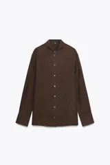 Camisa marrón de seda 100% con cuello solapa, manga larga con puños abotonados, bajo asimétrico redondeado y cierre frontal con botones.