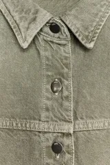 Cazadora de denim verde oliva, con cuello solapa, manga larga, bolsillos delanteros de plastrón y cierre frontal con botones metálicos.