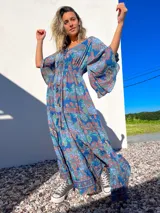 Vestido túnica largo de algodón con estampado de arabescos en tonos azules, rojos y verdes. Tiene escote en V con cordones y mangas acampanadas.
