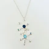 Collar con dije de pulpo plateado con detalles de circonitas azules y celestes, y cadena fina.