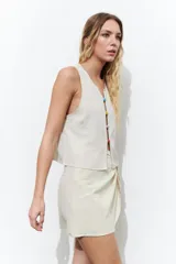 Minifalda color beige con diseño cruzado y nudo lateral.