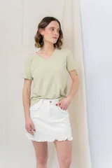 Minifalda blanca de denim con detalles de volados en los bolsillos delanteros y en el ruedo.