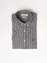 Camisa de hombre de manga corta, confeccionada en lino y algodón. Presenta un diseño a rayas verticales blancas sobre fondo azul grisáceo, cuello abotonado y bolsillo en el pecho con logo bordado.