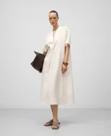 Vestido midi de lino color blanco, corte amplio, escote en pico con festón, manga corta y aberturas laterales.