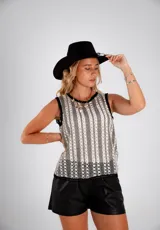 Blusa blanca de tejido calado, sin mangas y con cuello redondo ribeteado en negro.