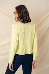 Chaqueta de cuero ecológico color vainilla, con cuello clásico, cierre frontal descentrado con cremallera metálica dorada y pespuntes decorativos.