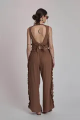 Conjunto de dos piezas color marrón, compuesto por un top sin mangas con volado en el ruedo y un pantalón ancho de tiro alto con volados decorativos a lo largo de las costuras laterales.