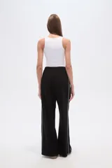 Pantalón deportivo negro de corte ancho y tiro alto, con cintura elástica y cordón ajustable. Presenta una raya blanca vertical a cada lado.