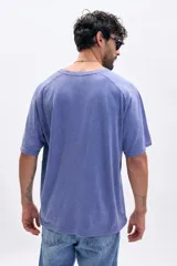 Remera de manga corta con mangas ranglán, color azul con efecto lavado o acid wash. Presenta cuello redondo y corte holgado.