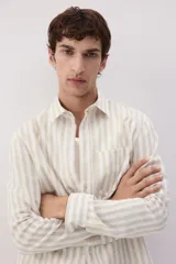 Camisa de manga larga con cuello inglés y bolsillo en el pecho. Diseño a rayas verticales en tonos beige y blanco. Corte estándar.