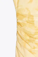 Vestido midi de tul color amarillo pálido con estampado floral, escote redondo y tirantes finos ajustables. Presenta detalle de frunces, forro interior y cierre lateral con cremallera oculta.
