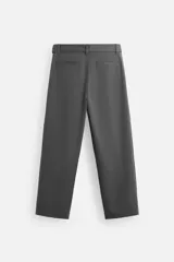 Pantalón negro de corte ancho con cinturón de tela con hebilla metálica y pliegues frontales.