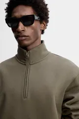Sudadera negra de algodón con cuello alto y cierre de cremallera frontal. Corte relaxed fit, manga larga y terminaciones en rib.