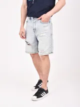 Bermuda de jean negro con roturas y corte a la rodilla.