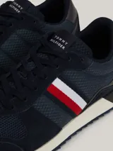 Zapatillas Tommy Hilfiger de estilo running, color azul marino con detalles en rojo, blanco y gris. Confeccionadas en poliéster con interior de poliéster, plantilla extraíble de goma termoplástica y poliuretano, y suela de goma dentada. Presentan cinta distintiva en el lateral, paneles con mezcla de texturas y parche con logo en la lengüeta.