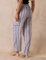 Pantalón de lino a rayas verticales en tonos beige, azul y blanco. Tiene pretina elastizada, bolsillos inclinados delanteros y bolsillo lateral tipo cargo.