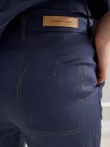Pantalón largo de lino color marrón, con corte cigarette, tiro alto, bolsillos laterales y traseros con pespuntes a la vista, y etiqueta de cuero con logo en la cintura.