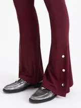 Pantalón de pierna recta color bordó, confeccionado en viscosa con elastano. Presenta cintura elastizada, costuras decorativas en el frente y broches metálicos con logo grabado en las botamangas.