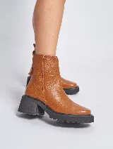 Bota corta de cuero color marrón, con cierre lateral, suela de goma negra y taco cuadrado.