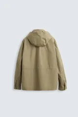 Parka color beige de tejido técnico ligero, corte relaxed fit, cuello alto con capucha plegable, manga larga con puños ajustables con botón a presión, cierre frontal con cremallera, cintura ajustable con elástico interno y múltiples bolsillos frontales de parche con solapa.