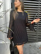 Vestido corto de encaje negro con mangas largas acampanadas.