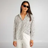 Blusa fluida blanca con estampado de lunares negros, de manga larga y corte suelto.