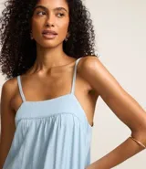 Vestido largo celeste de jeans con breteles finos, escote cuadrado, lazo en la espalda y abertura en la parte inferior.