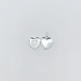 Dije relicario con forma de corazón, realizado en plata 925 y adornado con circonias.