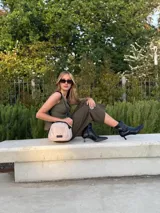 Bandolera pequeña de tela negra, con correa ancha ajustable y cierre superior.