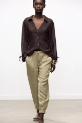 Pantalón jogger marrón de tiro alto con cintura elástica ajustable con cordones, bolsillos delanteros y puños elásticos en los tobillos.