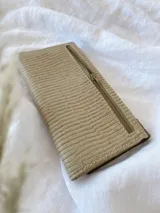 Billetera de cuero turquesa, blanco y beige con diseño texturizado. Tiene sistema de cierre con broche y monedero externo.