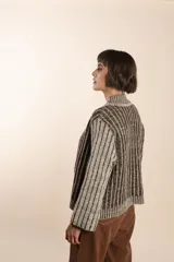 Cárdigan tejido a rayas verticales marrones y beige, con cuello esmoquin, cierre frontal con botones y corte holgado. Tejido en 100% lana fina sin teñir.