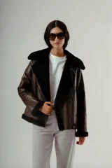 Chaqueta estilo aviador o biker de cuero marrón oscuro con forro y cuello de piel sintética negra. Presenta cierre asimétrico frontal y bolsillos laterales con cierre.